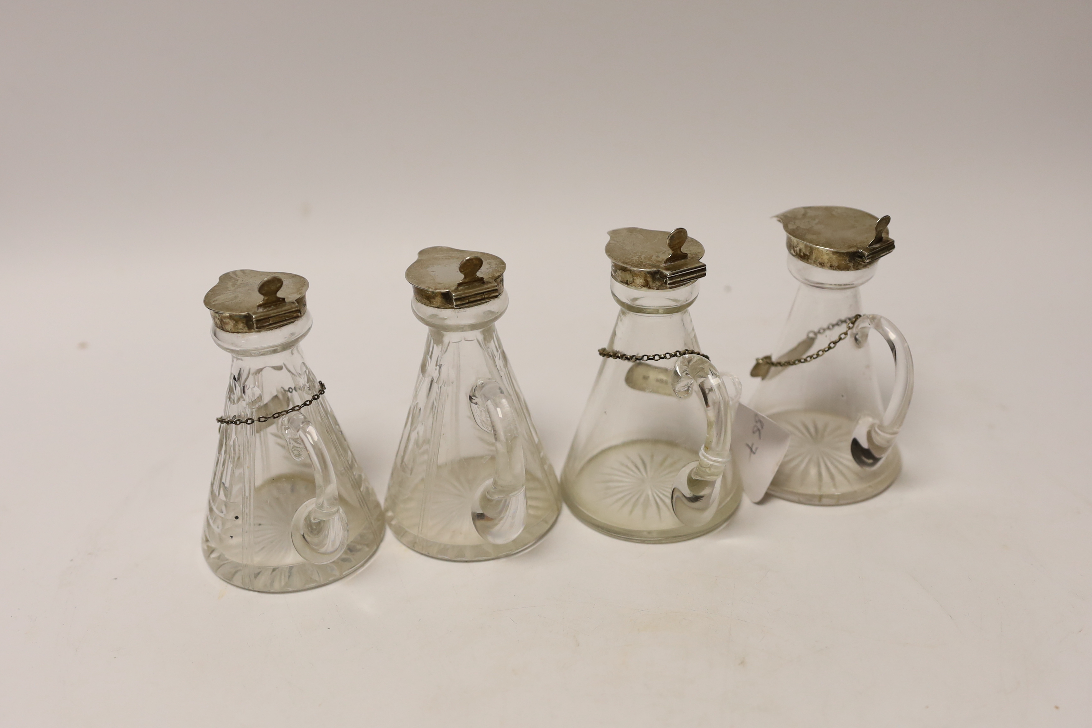 A pair of 1930's silver mounted glass whisky noggins by Goldsmiths & Silversmiths Co Ltd, London 1936, 11.1cm and two other earlier silver mounted glass whisky noggins, together with three silver whisky labels.